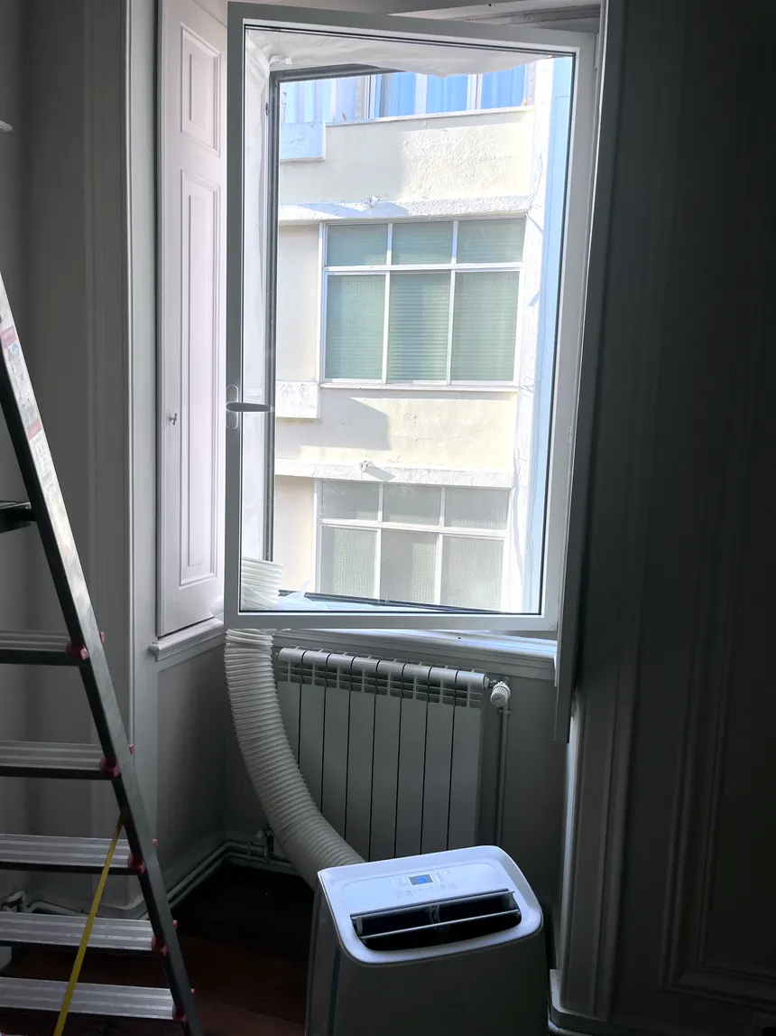Tubo de exaustão de ar condicionado portátil instalado numa janela basculante em Lisboa
