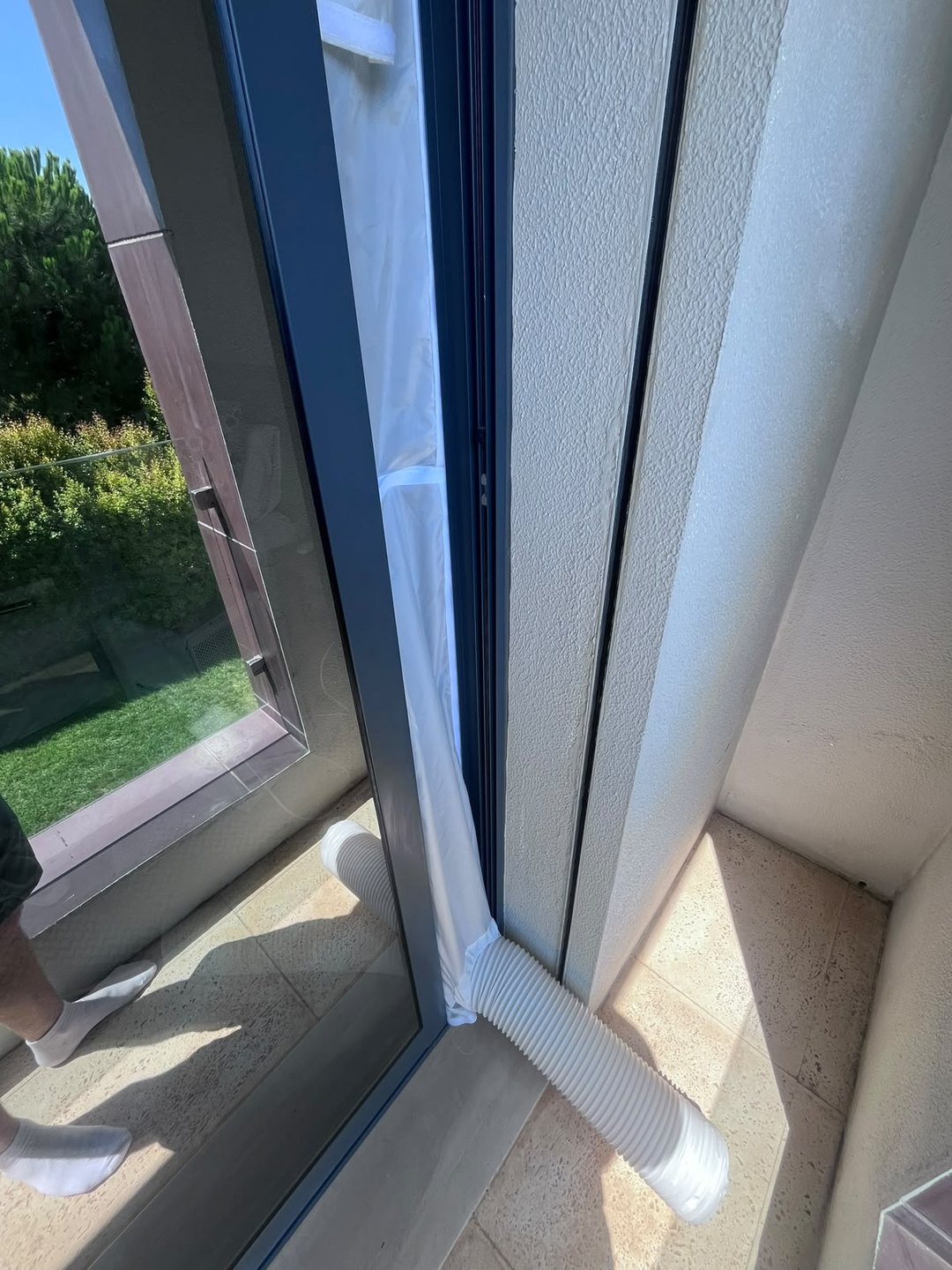 Exhaust hose of a portable air conditioner sealed into a sliding door with a window kit in a Cascais villa