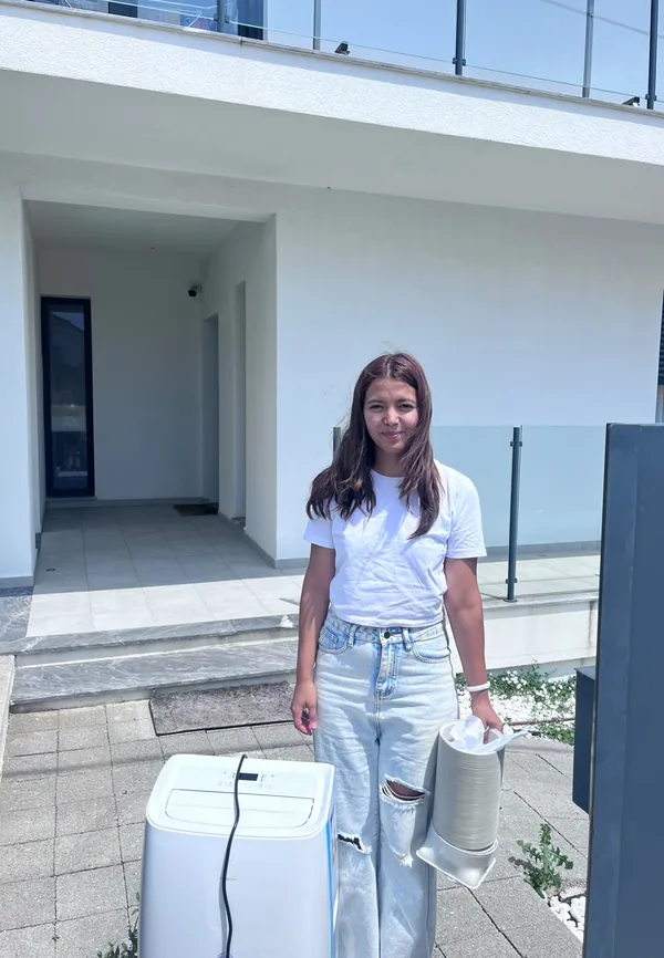 Renata da AC Rental Lisbon a entregar um ar condicionado portátil com kit de janela numa vivenda em Grande Lisboa