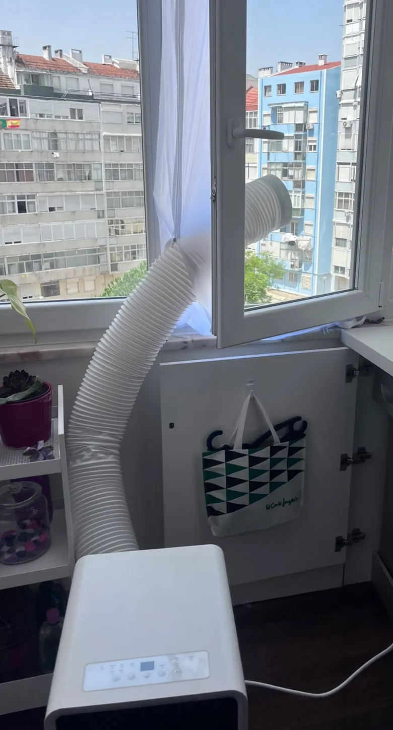 Kit de vedação de janela montado à volta da mangueira numa janela de batente em Lisboa, com vista para a cidade